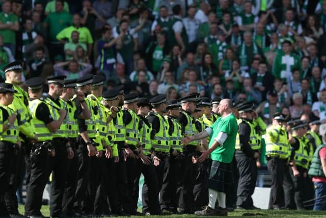 A Hibs fan talks to an officer as a police cordon forms on the Hampden pitch. Picture: Lynne Cameron/SportImage/PA Images