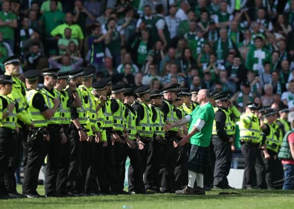 A Hibs fan talks to an officer as a police cordon forms on the Hampden pitch. Picture: Lynne Cameron/SportImage/PA Images
