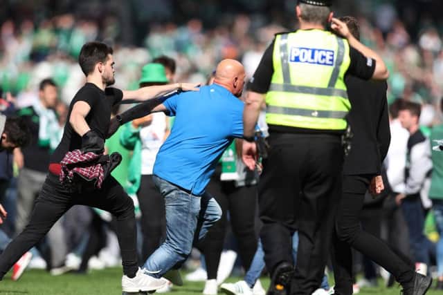 A policeman looks on as fans clash on the Hampden Park turf. Picture: Getty