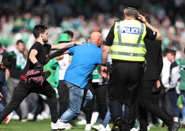 A policeman looks on as fans clash on the Hampden Park turf. Picture: Getty