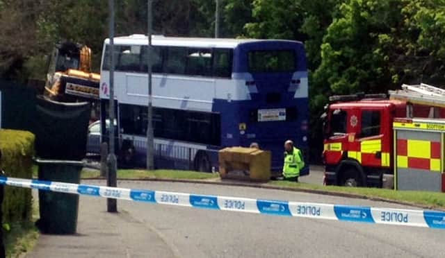 Police at the scene in Rutherglen, Glasgow, were a digger has fallen onto a car. Picture: SWNS