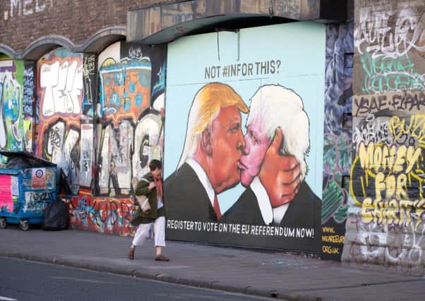 A woman passes a mural that has been painted on a derelict building in Stokes Croft showing US presidential hopeful Donald Trump sharing a kiss with former London Mayor Boris Johnson. Picture: Getty Images