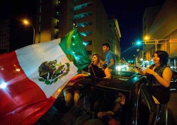 A woman waves the Mexican flag while driving past the Albuquerque Convention Center after a rally by Donald Trump. Picture: AP