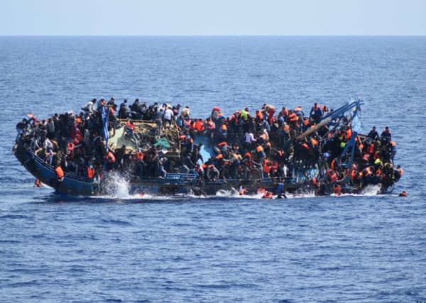 People jump out of a boat right before it overturns off the Libyan coast. Picture: AP