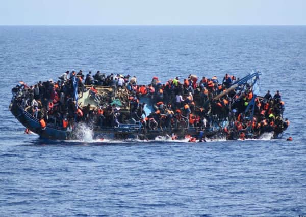 People jump out of a boat right before it overturns off the Libyan coast. Picture: AP