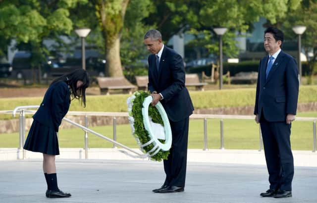 Obama (C) recieves a wreath from a student (L) beside Japanese Prime Minister Shinzo Abe (R) at the cenotaph in the Peace Momorial park in Hiroshima. Picture: AFP/Getty