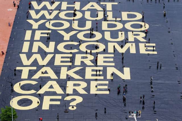 A huge poster reading What would you do if your income were taken care of? is pictured on the Plaine de Plainpalais square in Geneva, Switzerland. Picture: AP