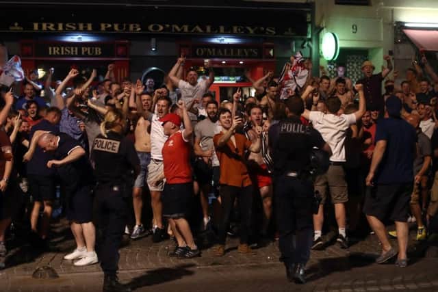 Police officers look on as England fans shout and chant outside a bar. Picture: Getty