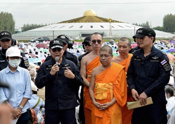 A member of the department of special investigationS addresses reporters as he stands with monks from the Wat hammakaya. Picture: AFP/Getty Images