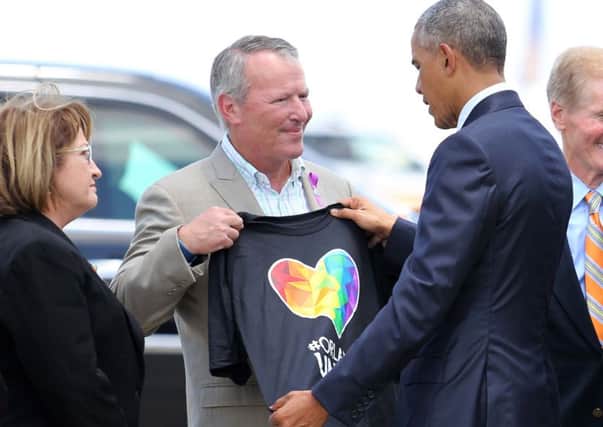 Barack Obama looks at a T-shirt that was presented to him by Orlando mayor Buddy Dyer (centre). Picture: PA
