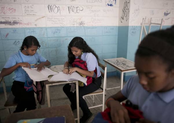 Maria Arias, centre, works with a classmate. The youngster has been robbed at gunpoint in school. Picture: AP