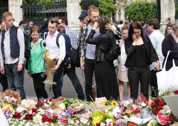 Members of the public look at flowers and tributes in Parliament Square. Picture: PA