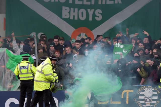 A steward removes a smoke canister from the pitch at Stair Park during a Stranraer V Celtic cup tie. Picture: SNS Group