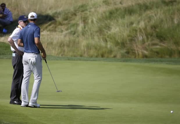 Dustin Johnson, right, talks to a rules official on the fifth green during the final round of the US Open. Picture: AP