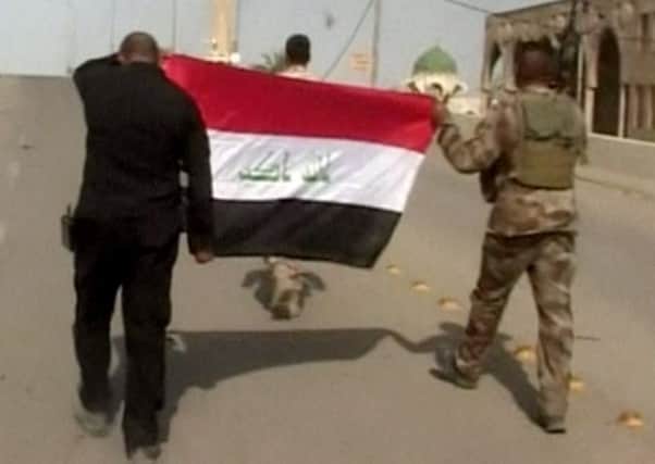 Iraqi soldiers carrying an Iraqi flag to hoist on buildings after a senior Iraqi commander declared Fallujah was fully liberated from Islamic State. Picture: AP