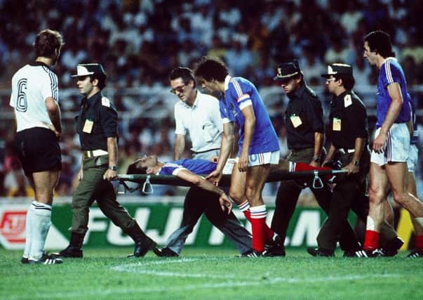 Michel Platini comforts France defender Patrick Battiston following a vicious collision with German goalkeeper Harald Schumacher during the 1982 World Cup semi-final in Seville. Picture: AFP/Getty Images