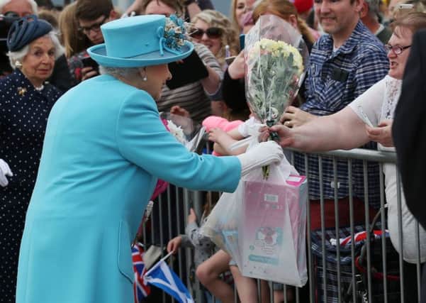 Queen Elizabeth II is given a plastic B&M bag with toys for her great-grandchildren. Picture: PA