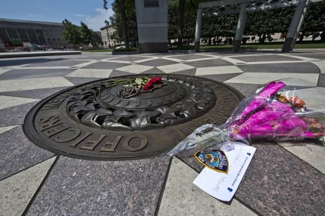 Five red roses on the bronze medallion with another bouquet of flowers and a note in support of the Dallas Police Department. Picture: AP