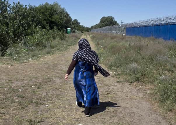 A woman walks next to border barriers at a makeshift migrants and refugees camp situated meters away from the Serbian border with Hungary. (AP Photo/Marko Drobnjakovic)