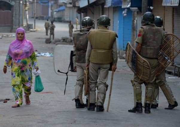 A Kashmiri Muslim woman walks past Indian policemen on a street during a curfew in Srinagar.
Picture: Getty Images