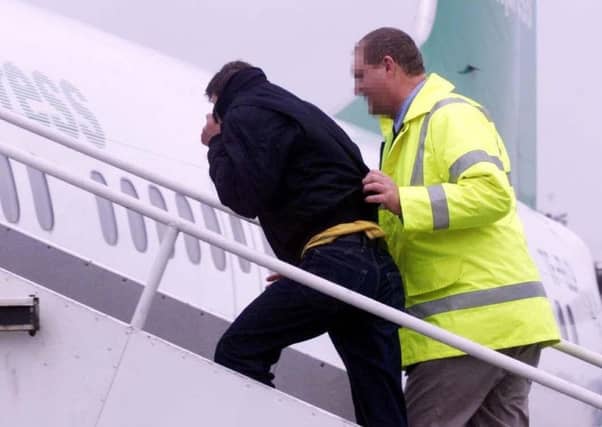 An unidentified official escorts a failed asylum seeker on a chartered plane at Stansted Airport. Picture: PA Photo/Sean Dempsey