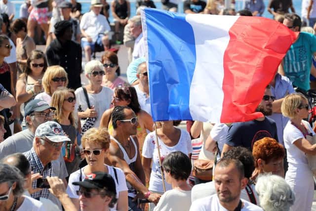 A man holds a French flag as people gather to observe a minute's silence on the Promenade des Anglais in Nice. Picture: AFP/Getty Images