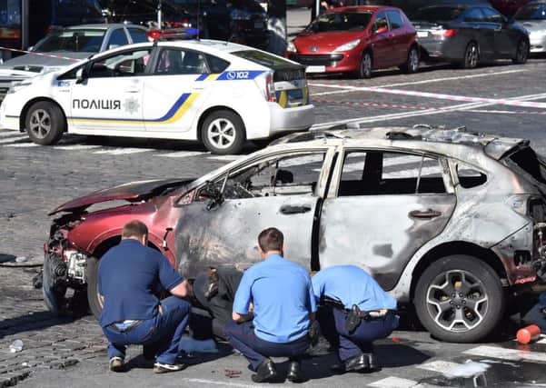 Experts check the burnt-out wreckage of Sheremets car after it exploded in Kiev. Picture: AFP