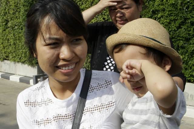 Noppawan "Ploy" Bunluesilp, with her son as she prepares to leave a Bangkok police station. Picture: AP