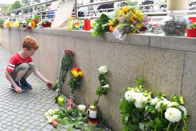 A little boy puts down flowers near a mall where the shooting took place. Picture: AP Photo/Kerstin Joensson