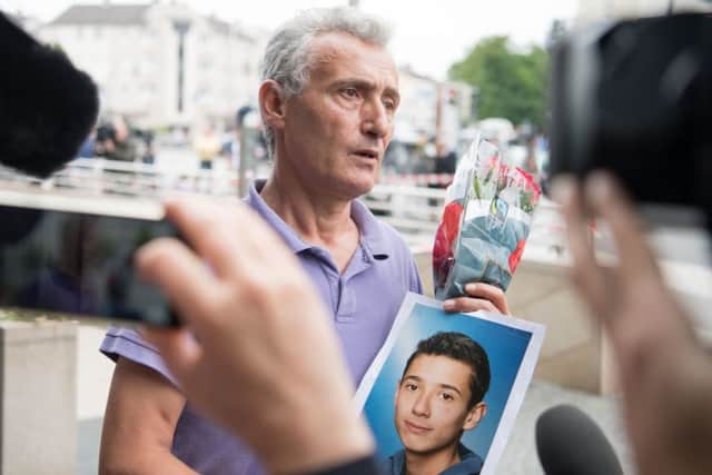 The father of a victim shows a picture of his son near the Olympia shopping centre  in Munich, southern Germany, where a shooting took place. Picture: AP Photo/Sebatian Widmann