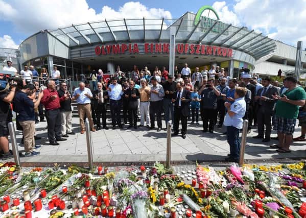 People said prayers yesterday at a memorial of flowers and candles laid at the Olympia Einkaufszentrum shopping centre. Picture: AFP/Getty Images