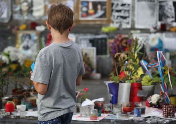 A boy stands in front of French flags and messages after a priest was killed in Normandy by Islamic State. Picture: AFP/Getty Images