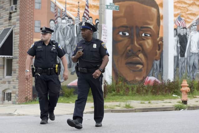 Baltimore police walk near a mural depicting Freddie Gray. Picture: AP
