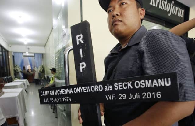 A protester holds a cross with name of death row prisoner Seck Osmanu on it in Jakarta. Picture: AP