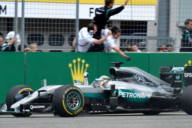Lewis Hamilton salutes his team before throwing aloft the trophy in delight on the podium. Picture: AFP/Getty Images