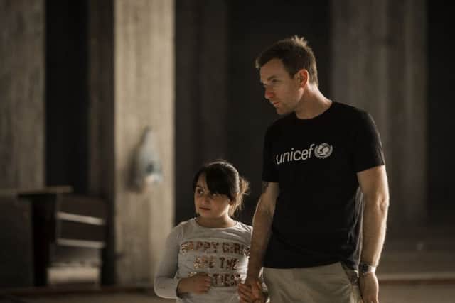 Ewan McGregor walks with Myrna, 10, inside an abandoned mall in Erbil. Picture: PA