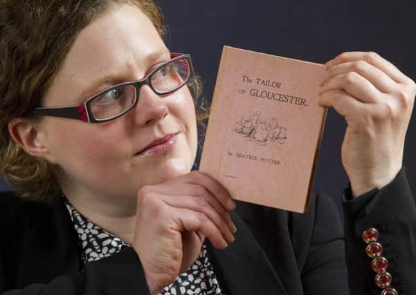 Cathy Marsden with a privately printed first edition of Beatrix Potters The Tailor of Gloucester. Picture: SWNS