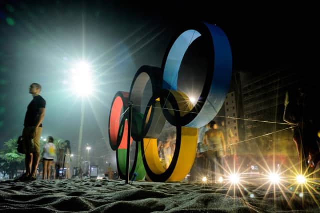 People pose for photographs near a large Olympic Rings display on Copacabana Beach in Rio. Picture: AFP/Getty Images
