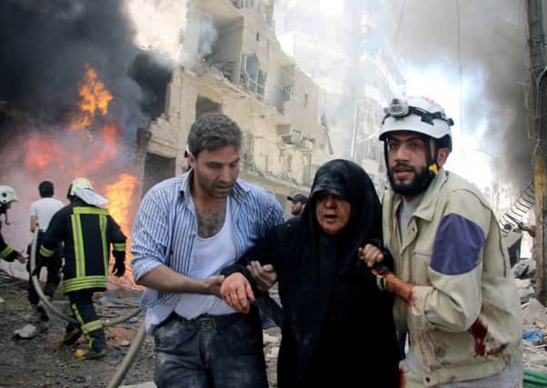 Syrian civil defense workers help an injured woman after warplanes attack a street in Aleppo. Picture: AP