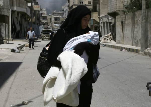 A woman carries her baby as civilians fleeing the IS-controlled zones arrive in the northern Syrian town of Manbij. Picture: AFP/Getty Images