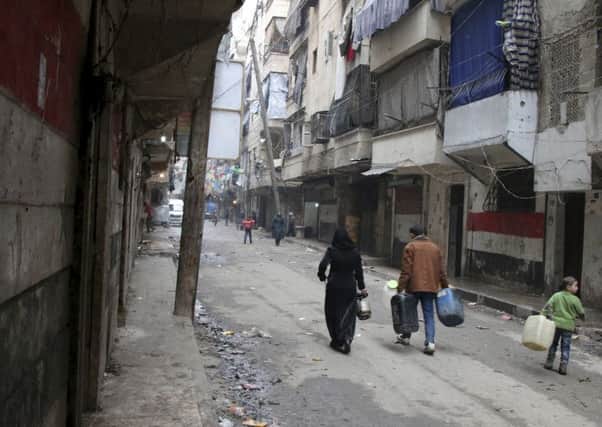 Civilians walk with containers for fuel and water in Aleppo. Picture: AP
