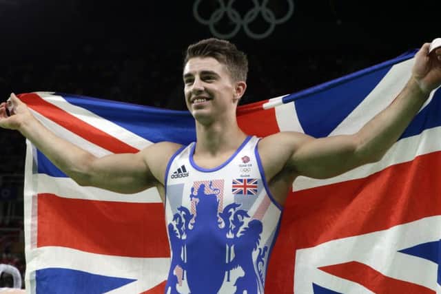 Britain's Max Whitlock stands with his national flag after winning gold in the pommel horse. Picture: AP