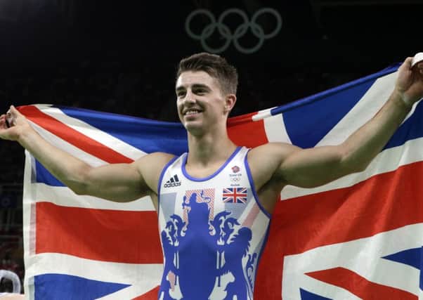 Britain's Max Whitlock stands with his national flag after winning gold in the pommel horse. Picture: AP