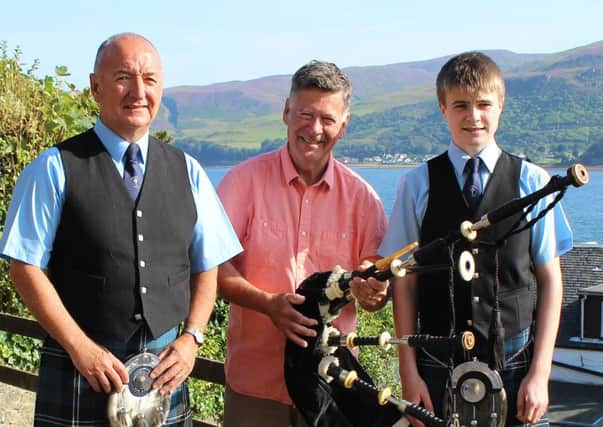 Bob Worrall, from Canada,  presents Calum McKillop, 14, with Archie McGeachy's cherished bagpipes
as Kintyre Schools Pipe Band Major Ian McKerral looks on.