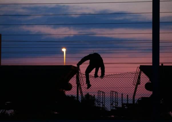 A migrant climbing over a fence on to the tracks near the Eurotunnel site at Coquelles in Calais. Picture: PA