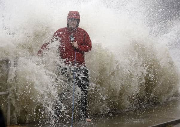 A news reporter doing a stand up near a sea wall in Cedar Key, Fla., is covered by an unexpected wave as Hurricane Hermine nears the Florida coast. Picture: AP Photo/John Raoux