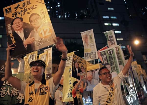 Pro-democracy candidate Tam Tak-chi, right, of People Power waves to supporters at polling station. Picture: AP