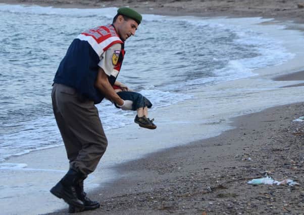 A Turkish police officer gently carries the body of Aylan Kurdi. Picture: Getty