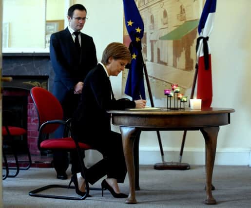 Consul General Emmanuel Cocher watches as Sturgeon signs a book of condolence after the Paris terrorist attacks last November. Picture: Lisa Ferguson