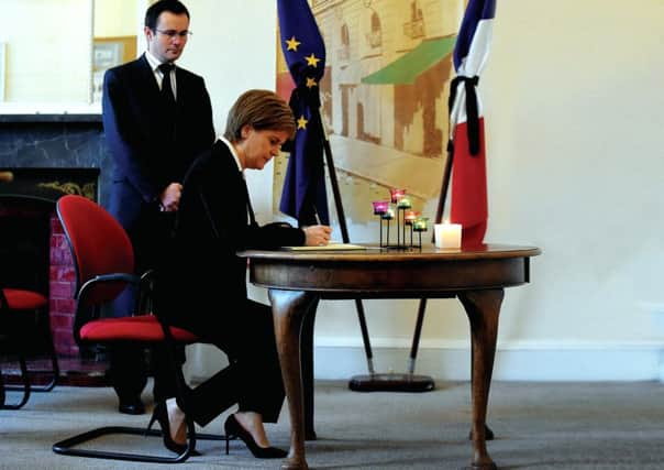 Consul General Emmanuel Cocher looks on as Sturgeon signs a book of condolence after the Paris terrorist attacks last November. Picture: Lisa Ferguson